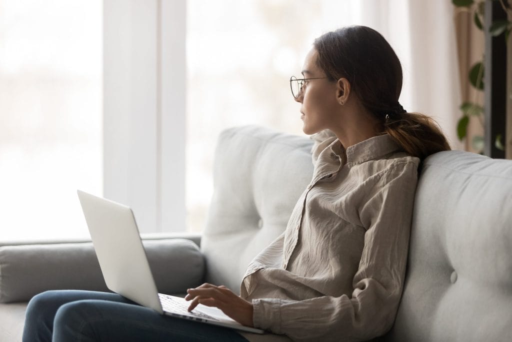 women wondering on a sofa, looking outside the window