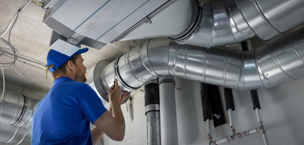 technicien CVC installant un système de conduits pour ventilation et air