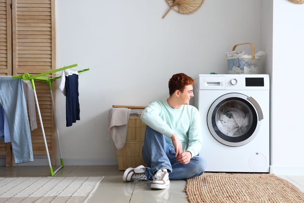 young,man,sitting,near,washing,machine,at,home