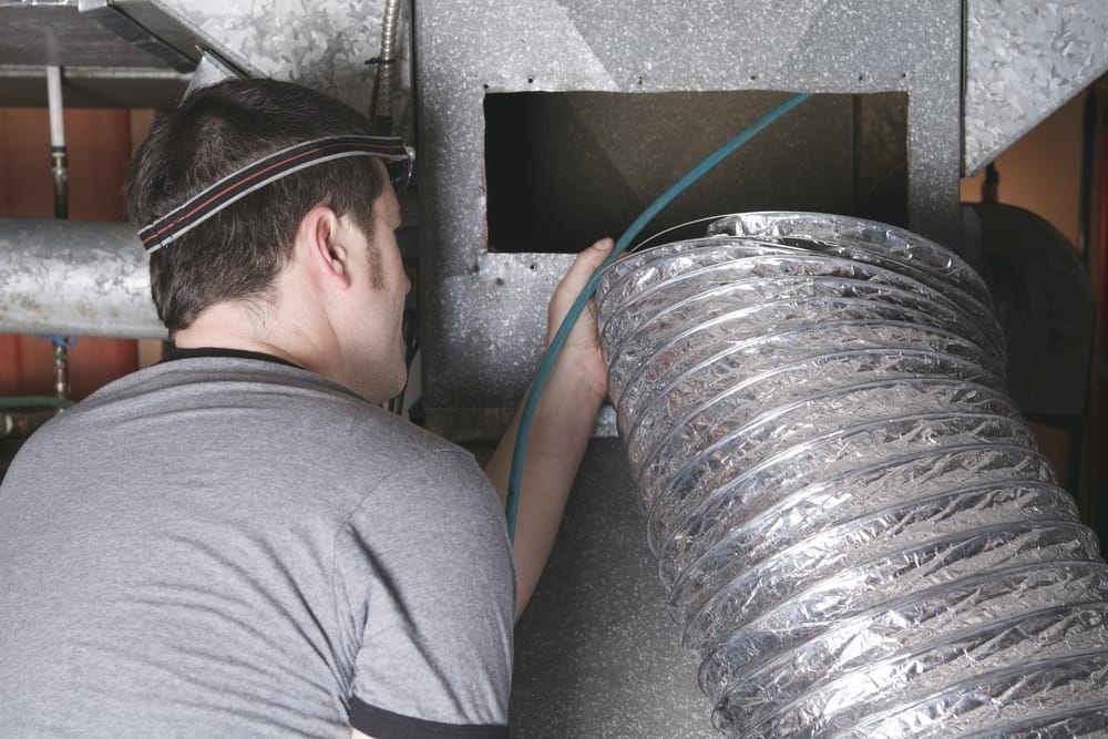 un nettoyeur de ventilation au travail avec un outil